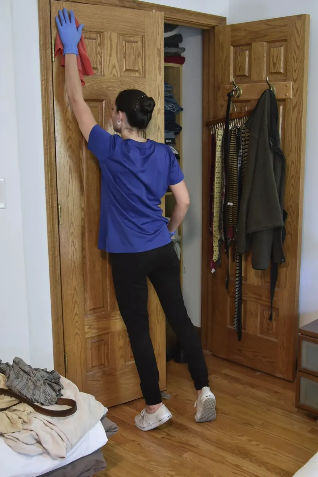 A Happy Maids technician hand-dusting the top of a bedroom door
